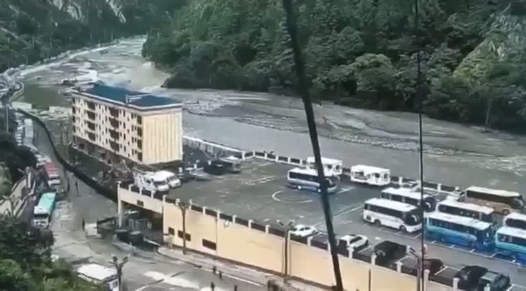 A Bus Lot Beside a River Disappears Behind a Wall of Dust