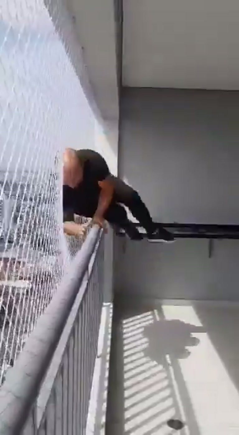 Man Climbs Over High-Rise Balcony Railing Beside Safety Net