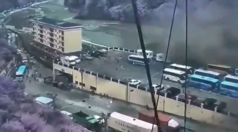 A Bus Lot Beside a River Disappears Behind a Wall of Dust